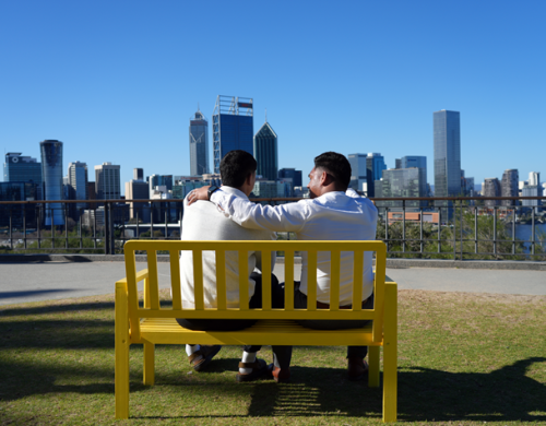 Two people on a bench talking supporting each other with a hand on the other's shoulder