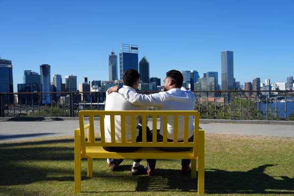 Two people on a bench talking supporting each other with a hand on the other's shoulder