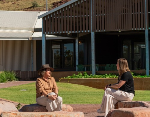 Two people sitting outside on rocks in Karratha talking