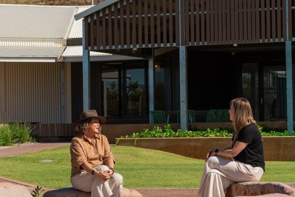 Two people sitting outside on rocks in Karratha talking