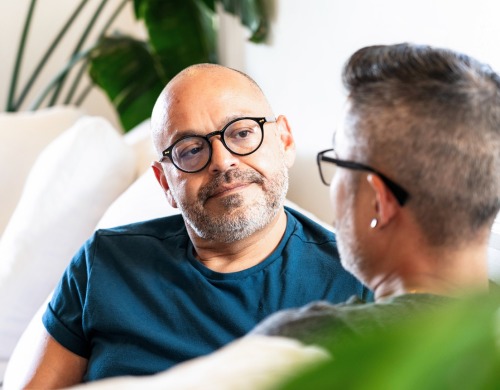 Two people sitting on a couch talking with one another