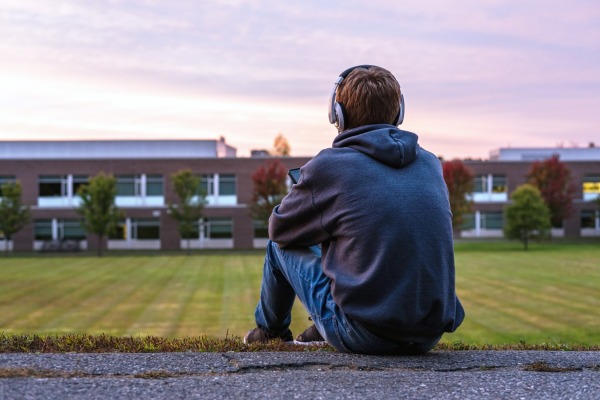 A person sitting facing a field with headphones on