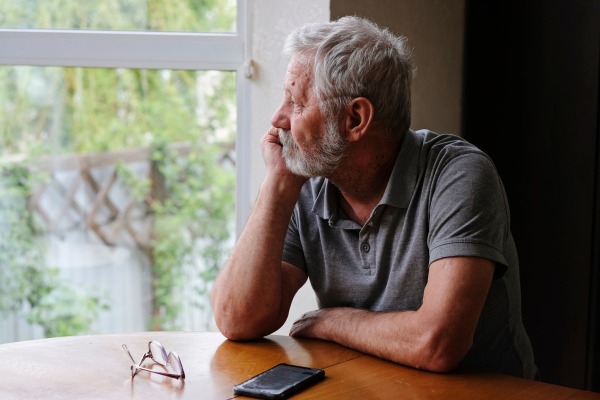 Man sitting at a table looking out the window deep in thought