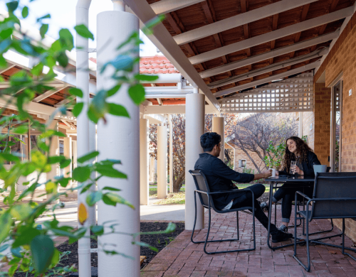 Two people sitting under a patio chatting