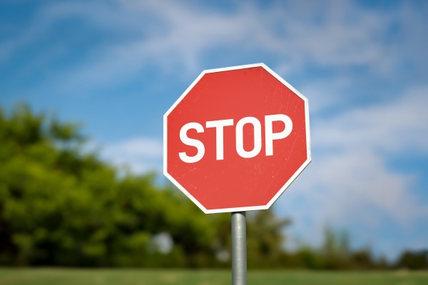 A stop sign with a tree in the background and blue sky