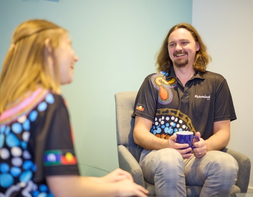 A man and woman sitting and talking to each other smiling