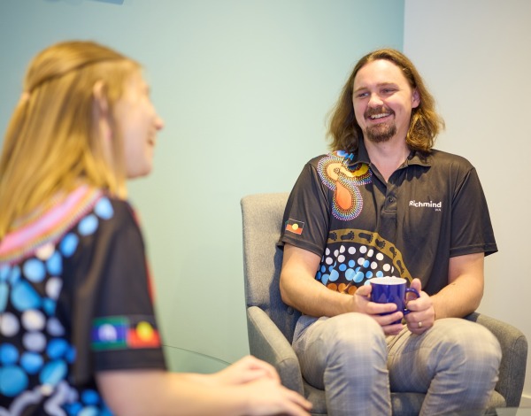 A man and woman sitting and talking to each other smiling