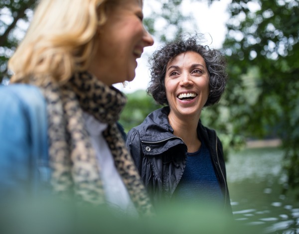 Happy mature woman looking at friend in forest.